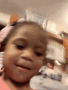 a little girl with a pink headband on her head is smiling for the camera .
