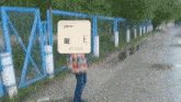 a person is standing in front of a fence with an amd fx box in front of their face