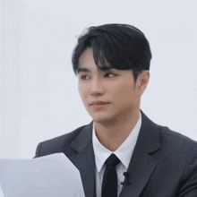 a man in a suit and tie holds a piece of paper in his hand