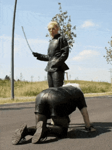 a woman in a leather jacket is kneeling down on the street with a whip