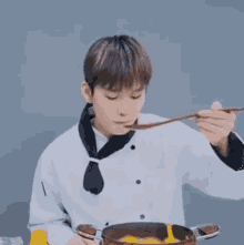 a chef is eating food from a pot with a spoon .