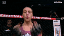a female fighter is clapping in front of a banner that says " fighters lea "