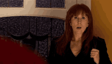 a woman with red hair is standing in front of a door with a stained glass window
