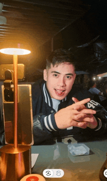 a young man sitting at a table with a lamp and a phone that has the number 18 on it