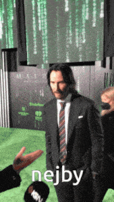 a man in a suit and tie is being interviewed on a green carpet with nejby written in the corner