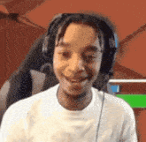 a young man wearing headphones is smiling in front of a green screen