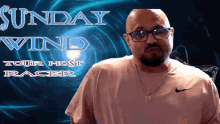 a man wearing glasses stands in front of a sign that says " sunday wind "
