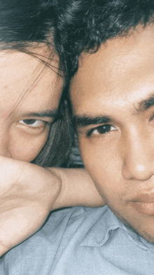 a close up of a man 's face with a woman 's arm around his neck