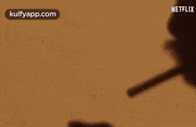 a shadow of a person holding a pen with a netflix logo on the bottom