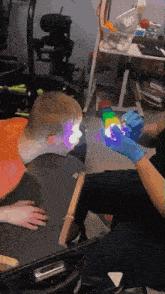 a person wearing blue gloves holds a cube in front of a child in a wheelchair