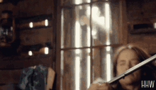 a woman playing a violin in front of a window with the letters hw visible