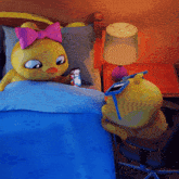 a yellow stuffed animal with a pink bow is looking at a phone