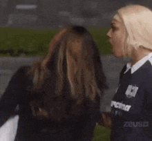 a couple of women are standing next to each other and one of them is shouting .