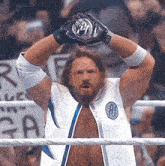 a wrestler in a white and blue outfit holds up a coin with the letter a on it