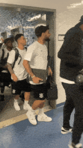 a group of men are walking down a hallway and one of them has a nike logo on his shorts