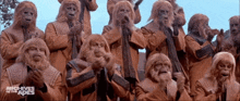 a group of monkeys are standing next to each other in a scene from the movie archives of the apes .