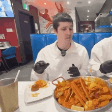 a man wearing black gloves is eating crab legs