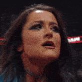 a woman is holding a wrestling belt in front of a crowd with a sign that says raw behind her