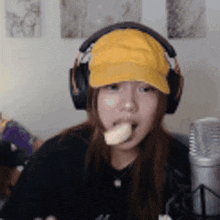 a woman wearing a yellow hat and headphones is eating a banana .