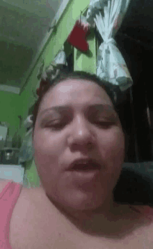 a woman in a pink shirt is making a funny face in front of a green wall