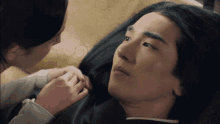 a woman is touching a man 's face while laying on a couch