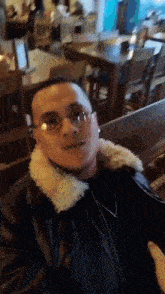 a man wearing glasses is sitting at a table in a restaurant