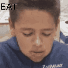 a boy in a blue shirt with the word eat written on his forehead