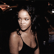 a woman in a black tank top with a necklace around her neck