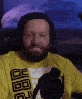 a man with a beard wears headphones and a yellow shirt that says jbbq on it