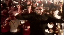 a man in a black jacket is dancing in front of a crowd .