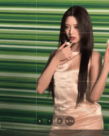 a woman in a pink dress holds a white object in front of a green wall