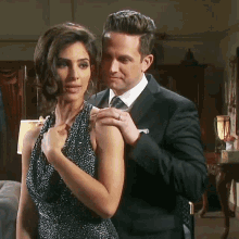 a man in a suit adjusts a woman 's dress