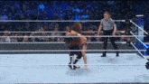 a referee is standing in the middle of a wrestling ring while two wrestlers are wrestling in front of a crowd .