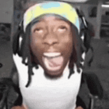 a man wearing headphones and a hat is sitting in a chair with his tongue hanging out .
