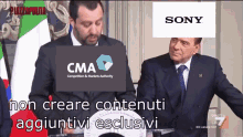 two men are sitting at a podium with cma and sony logos on them