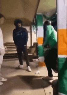 a group of people are standing in a hallway and one of them is wearing a green hoodie