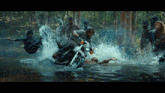 a man is riding a motorcycle through a flooded forest