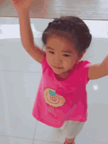 the little girl is wearing a pink shirt with a lollipop on it