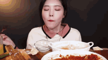 a woman is sitting at a table with plates of food and a glass of water .