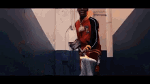 a man in a red jacket is standing in a hallway with a mop .