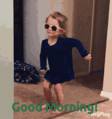 a little girl wearing sunglasses and a blue dress is dancing in a room with the words good morning behind her