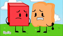 a red block and an orange block are standing next to each other in a grassy field .