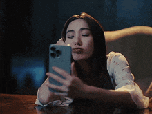 a woman is blowing a kiss while taking a selfie on her phone
