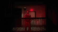 a man in a red shirt is standing on a balcony