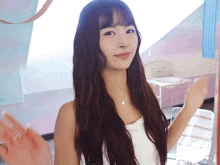 a woman with long brown hair and a white tank top