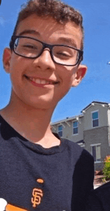 a young boy wearing glasses and a san francisco giants t-shirt is smiling for the camera .