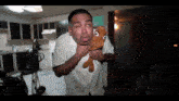 a man in a white shirt is holding a stuffed animal in his mouth