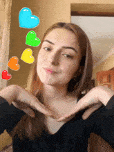 a girl making a heart shape with her hands with hearts floating above her