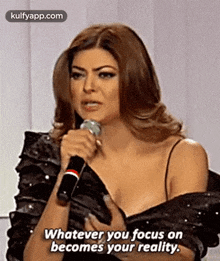a woman is holding a microphone and talking into it .