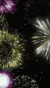 a fireworks display with purple yellow and white fireworks in the night sky